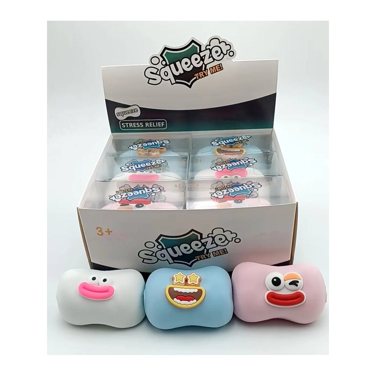 White, blue, and pink soap-shaped squishies with funny faces in front of a display box