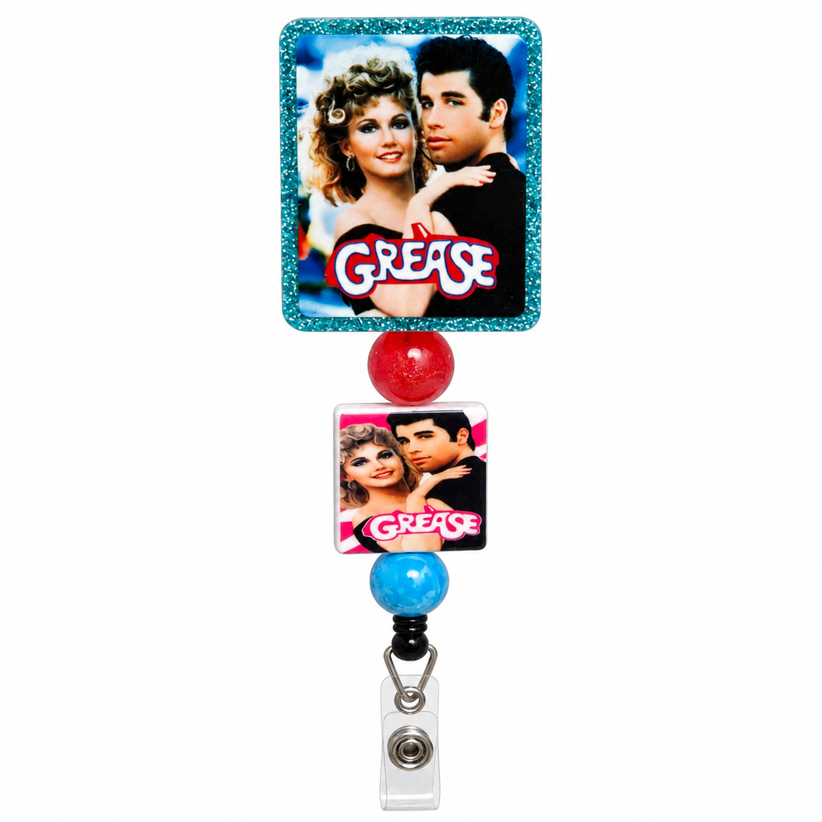 Grease movie beaded badge reel featuring Sandy and Danny with turquoise glitter border, matching Grease charm, red bead, blue bead, and clear ID strap