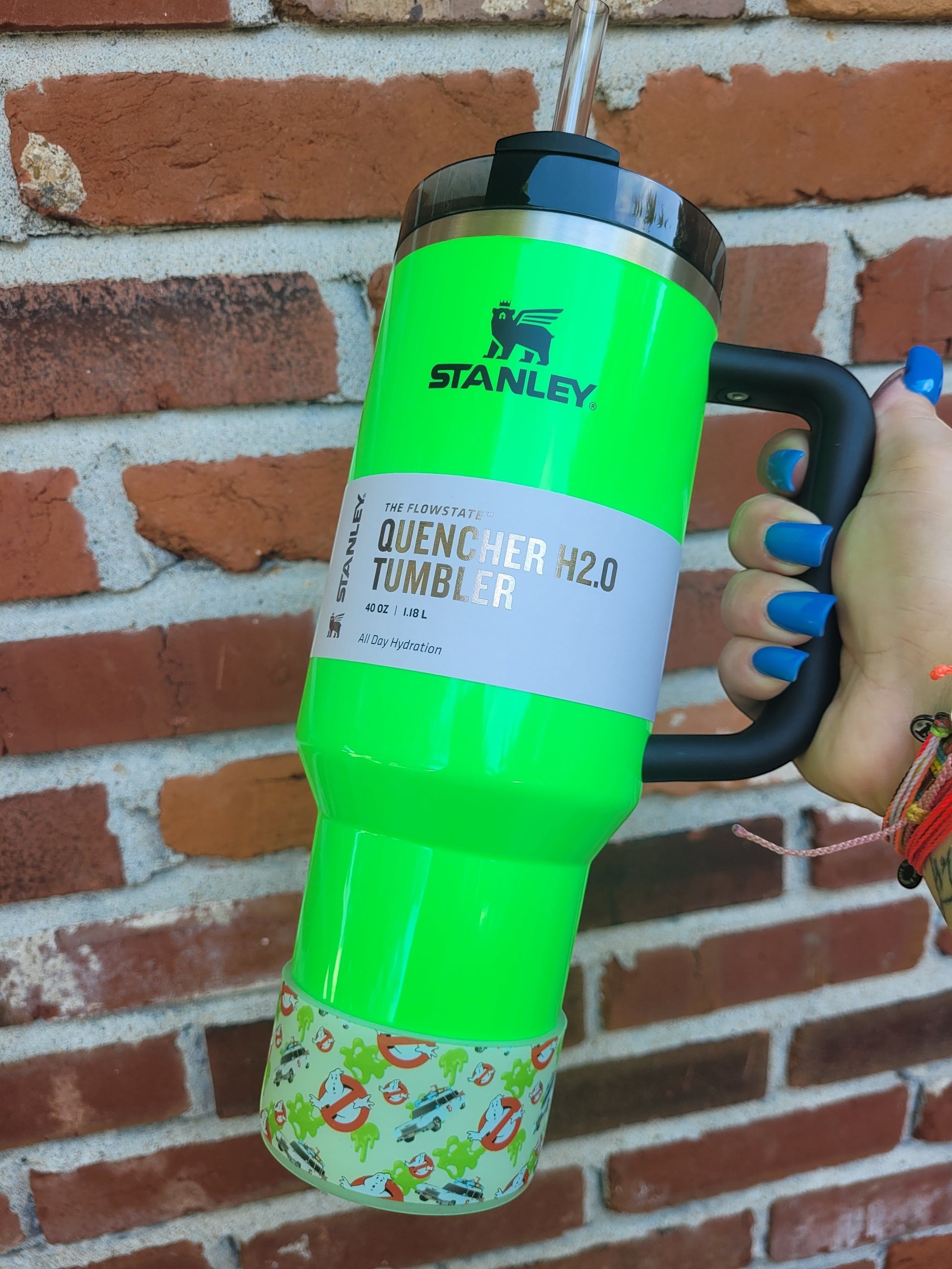 THE SALTY CHIC Ghostbusters silicone tumbler boot on a bright green Stanley Quencher cup against a brick wall